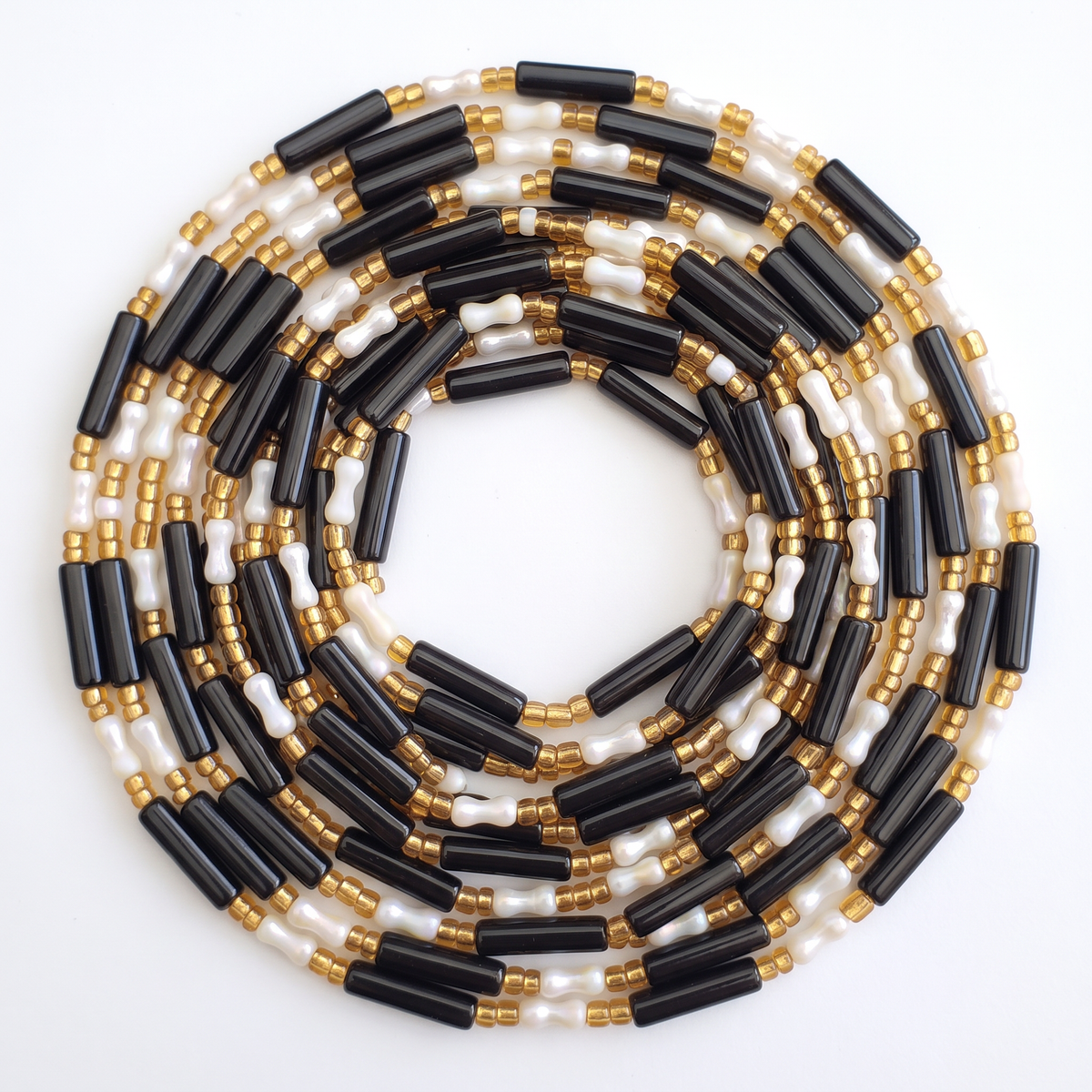 Rond opgerolde zwarte en parelwitte waistbeads met gouden details